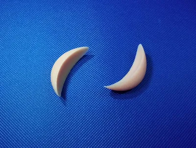 Two solid silicone chin implants displayed on a blue background